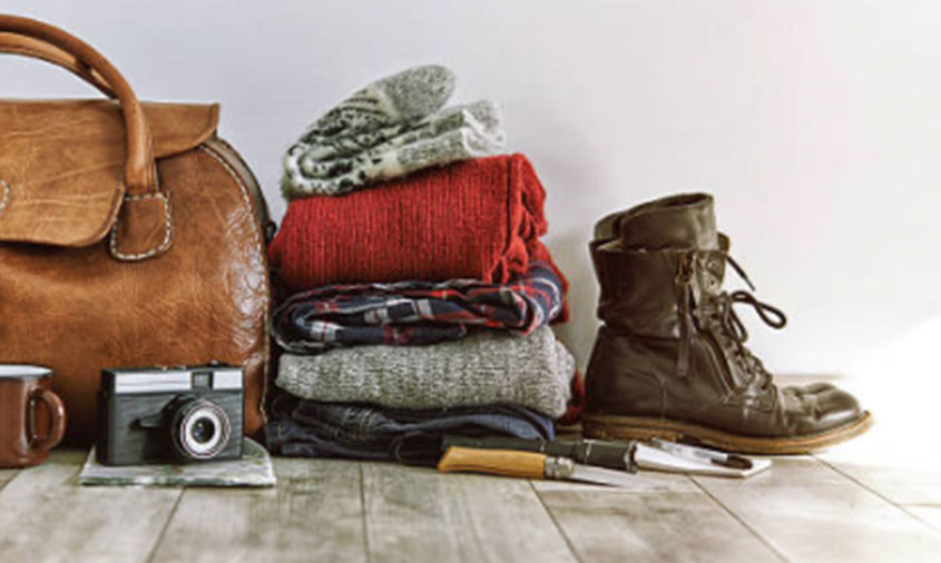A stack of clothes, shoes and a camera